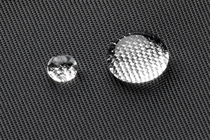 Two water droplets on a textured nylon weave twill surface, one larger and more reflective than the other. Shows water resistance.